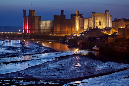 Caernarfon Castle at low tide in the town of Caernarfon in Gwynedd on the north coast of Wales in the United Kingdom. Dates from 1123.