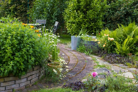 herb spiral in the garden with fresh herbs and flowers