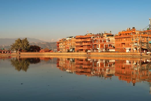 Golden hour at the Na Pukhu Lake, Pond in Bhaktapur, apartment, residential houses, buildings, dwellings are reflecting perfectly in the smooth surface of the water Bhaktapur, Nepal 2022