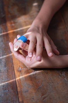 Close-up of the hands of an unrecognizable young boy applying a corrective splint to the little finger of his right hand. Copy space in vertical composition.