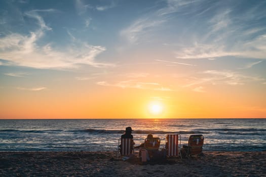 А family is watching sunset on a beach in Venice, Florida