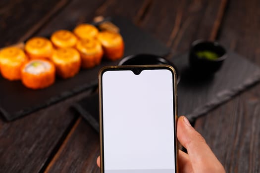 Hands taking picture of sushi japan food with smartphone. Copy space and empty space for advertising.