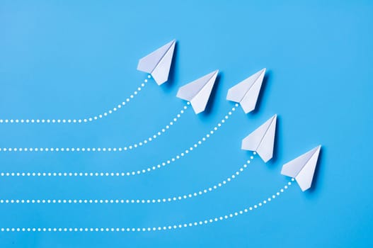 White paper airplane leading the rest of the white paper airplanes with blue cover background. Leadership concept.