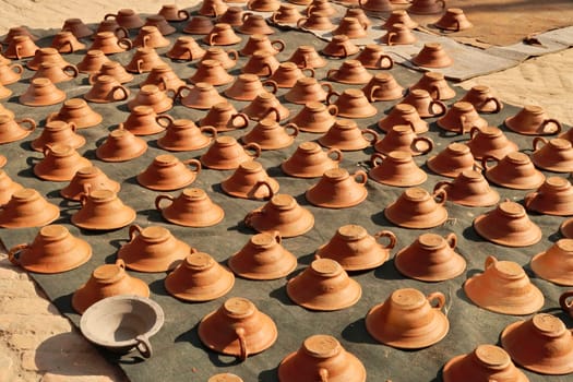 Many clay pots, vessels, bowls placed on a mat to dry in the sun at Pottery Square, Talako Tole in Bhaktapur, Nepal 2022