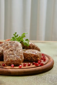 Close-up view of traditional Georgian raw beef cutlets - Apkhazura, wrapped in fat net decorated with pomegranate seeds