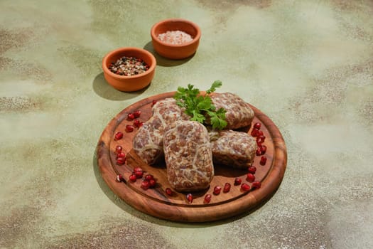 Georgian raw beef cutlets - Apkhazura, wrapped in fat net decorated with pomegranate seeds and cilantro