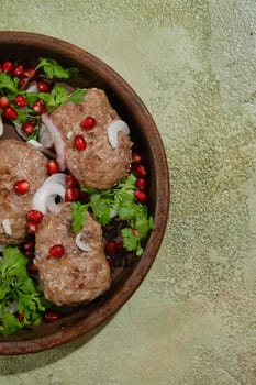 Traditional Georgian clay or stone frying pan with minced beef patties decorated with pomegranate seeds and cilantro