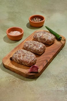 Georgian food: raw beef or lamb cutlets - Apkhazura with spice and herbs on wooden chopping board