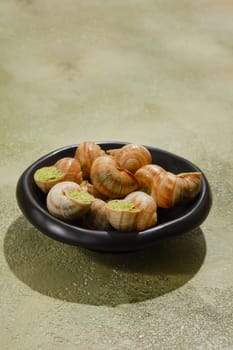 Black plate full of Escargot snails stuffed with spicy butter and cilantro