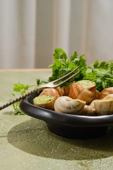 French gourmet food - Escargot snails baked in sauce on a plate