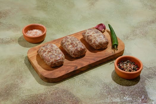 Raw beef or lamb patties - Apkhazura on wooden chopping board