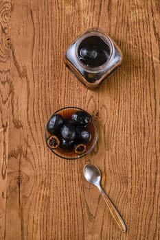 Overhead view of wooden table with saucer and jar with homemade preserved walnut jam