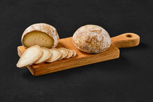 Traditional whole and sliced homemade Georgian cheese Dambalkhacho on wooden cutting board
