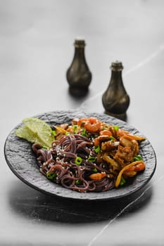 Black rice noodles with champignon and prawns in black plate
