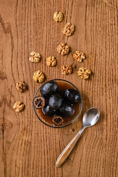 Overhead view of saucer with homemade preserved walnut jam and walnut kernels scattered on wooden background