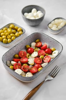 Mozzarella, tomato and olives salad seasoned with olive oil and balsamic vinegar