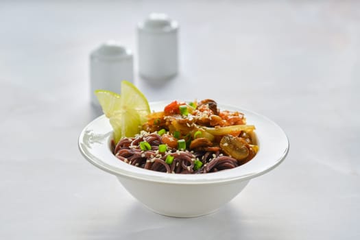 Spicy black rice noodles with prawns on marble background