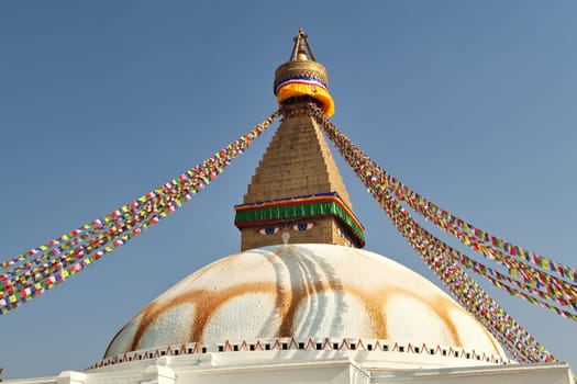 The upper part of the Boudhanath Stupa, many colorful prayer flags are attached to it, Kathmandu, Nepal 2022