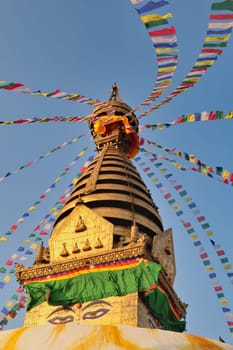 Many colorful prayer flags are attached to the golden top of the Swayambhunath Stupa, Temple with a face on it, Kathmandu, Nepal 2022