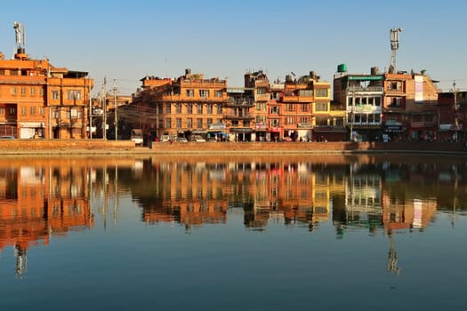 Apartment, residential houses, buildings, dwellings are reflecting perfectly in the smooth surface of the water of the Na Pukhu Lake, Pond, Bhaktapur, Nepal 2022