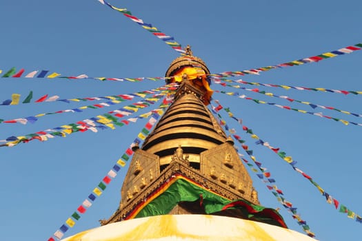 The golden top of the Swayambhunath Stupa, Temple, decorated with many colorful prayer flags, Kathmandu, Nepal 2022