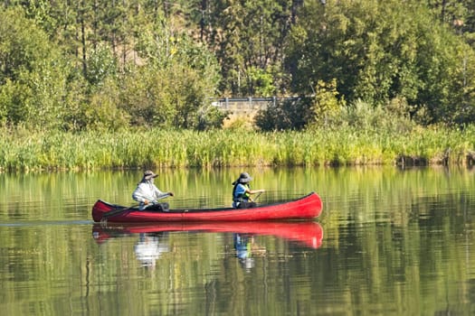 An editorial photo of a mature couple paddling the canoe on Coeur d'Alene Lake in north Idaho.