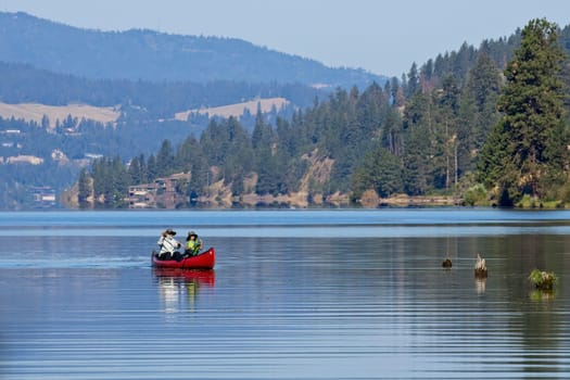 An editorial photo of a mature couple paddling the canoe on Coeur d'Alene Lake in north Idaho.