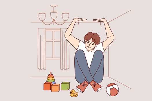 Boy suffers from claustrophobia, feeling pressure of walls and sitting in small room with scattered toys. Problem of claustrophobia in person with panic attack associated with negative memories