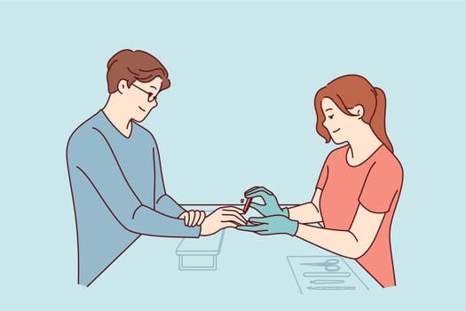Woman does manicure for man who cares about nail hygiene and well-groomed hands, or absence of uncut cuticles. Specialist processes fingernails with file during manicure session for guy