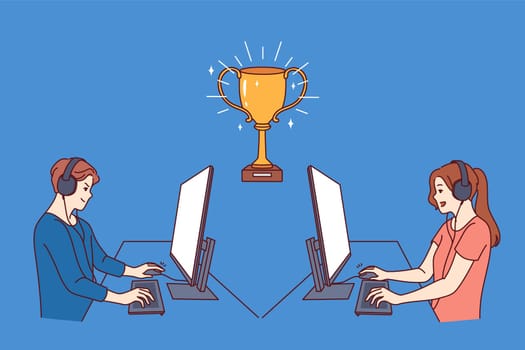 Gamers participate in esports video game tournament, sitting at tables with computers near gold cup. Guy and girl gamers compete to control virtual characters in shooters or RPG quests