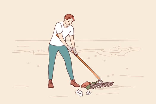 Man volunteer cleans beach of trash to prevent ocean pollution from plastic and bottles. Guy is volunteer trying to save nature and environment from pollution causing climate change.