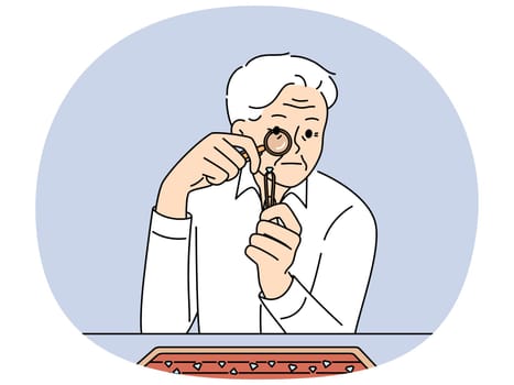 Elderly man jeweler examines diamond through magnifying glass checking gems for authenticity. Gray-haired worker in jewelry workshop chooses diamond to create necklace or engagement ring.