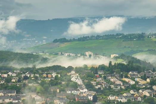 Dark storm clouds over the city of Trier in Germany, landscape with vineyards, agriculture field and forest, rainy weather in summer