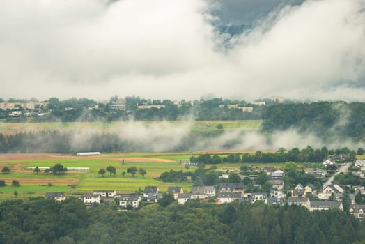 Dark storm clouds over the city of Trier in Germany, landscape with vineyards, agriculture field and forest, rainy weather in summer