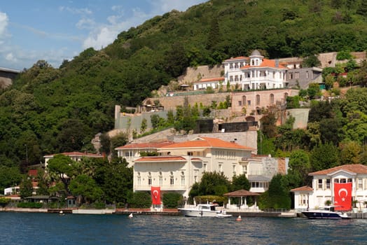 View from Bosphorus strait of the green mountains of the Asian side, with traditional houses and dense trees in a summer day, Istanbul, Turkey