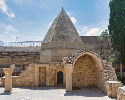 The historical Mausoleum of Seyid Yahya Bakuvi, featuring a distinctive conical roof and ancient stone architecture amidst the serene atmosphere of the Old City, Icherisheher, in Baku, Azerbaijan
