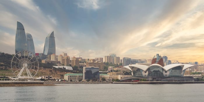 The Baku Eye and Flame Towers rise majestically beside Deniz Mall, reflecting the vibrant atmosphere of Baku, Azerbaijan, at sunset