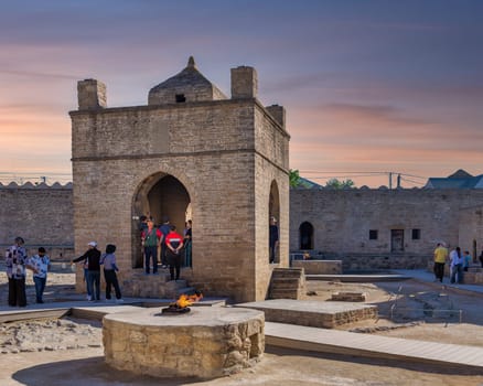 Baku, Azerbaijan - May 9, 2024: Tourists gather in the courtyard of the ancient Ateshgah Fire Temple, in the historical architecture during sunset