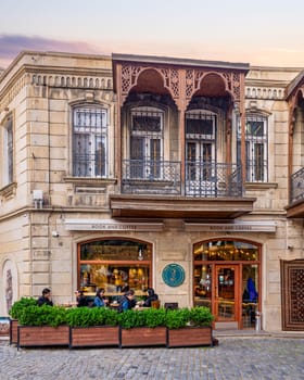 Baku, Azerbaijan - May 4, 2024: Visitors enjoy drinks and reading while relaxing at a cozy Book and Coffee cafe in the historical Old City, or Icherisheher, before sunset