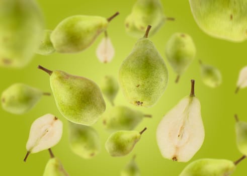 Halves and whole green pears levitate on a green background