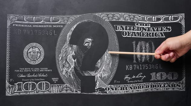 A chalk drawing of a US hundred dollar bill and a hand holding a pencil, a concept of uncertainty in the global or national economy, especially during periods of financial crises.