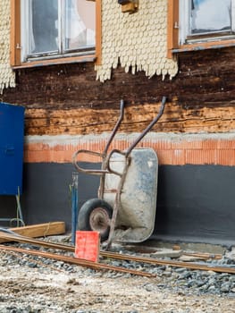Reconstructing construction site of a wooden house in Bavaria with a wheelbarrow placed against the wall.