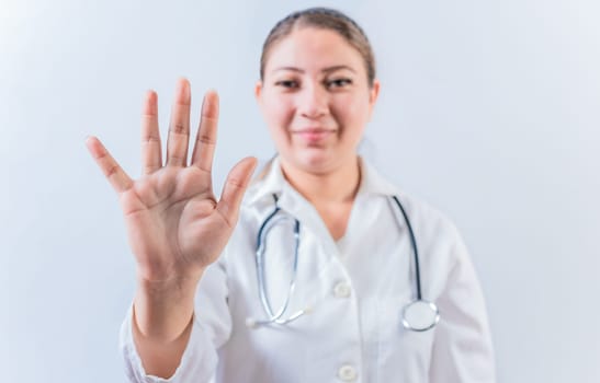 Female doctor counting number FIVE isolated. Young female doctor counting number 5 on isolated background