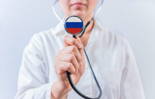 Female doctor holding stethoscope with with Russia flag. Russia health and care concept