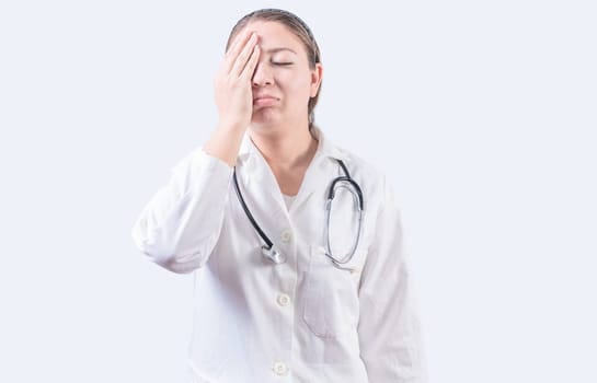 Stressed female doctor with hand on forehead isolated. Exhausted young female doctor with hand on forehead