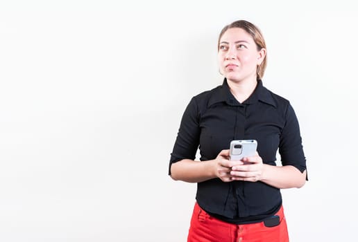 Thoughtful young woman holding phone isolated. Pensive latin girl holding smart phone on white background
