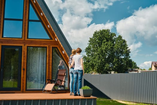 Rear side view of two women standing on terrace of tiny house