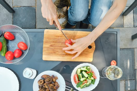 Overhead view of unrecognizable woman preparing salad outdoors while sitting in backyard