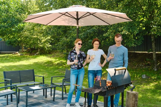 Family gathered next to a barbecue grill on the lawn