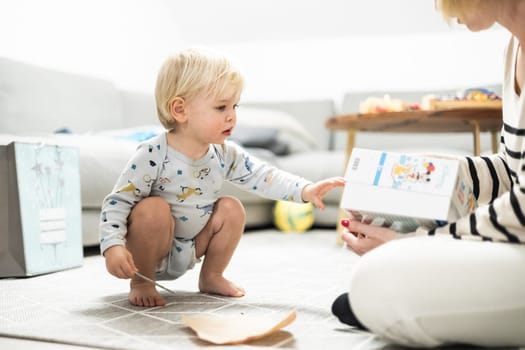 Parents playing games with child. Little toddler doing puzzle. Infant baby boy learns to solve problems and develops cognitive skills. Child development concept.